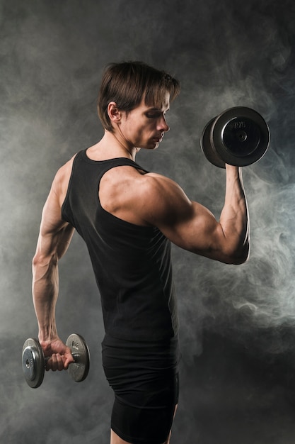 Side view of muscly athletic man holding weights