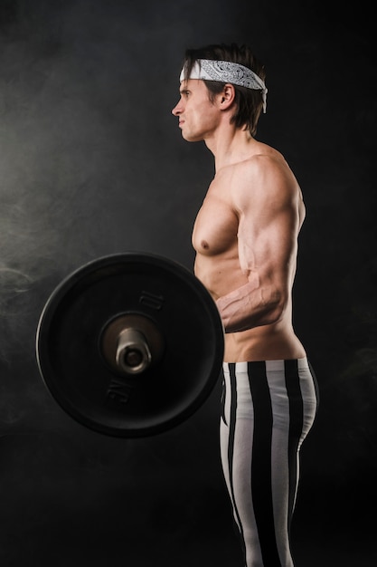 Side view of muscly man lifting weights