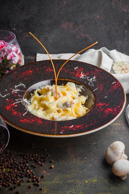 Side view mushroom pasta with champignon and black pepper grains in round plate