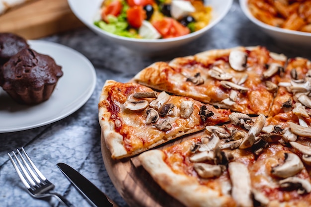 Side view mushroom pizza with tomato sauce cheese salt pepper and champignon on a board