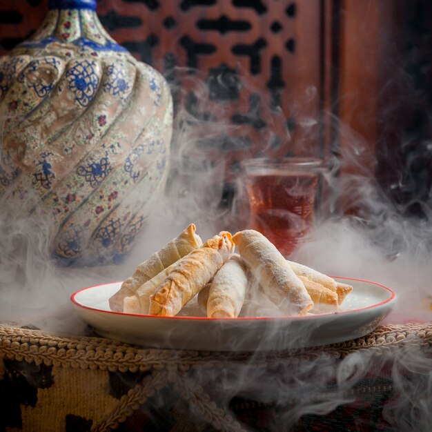 Side view mutekke with glass of tea and lemon and vase in table