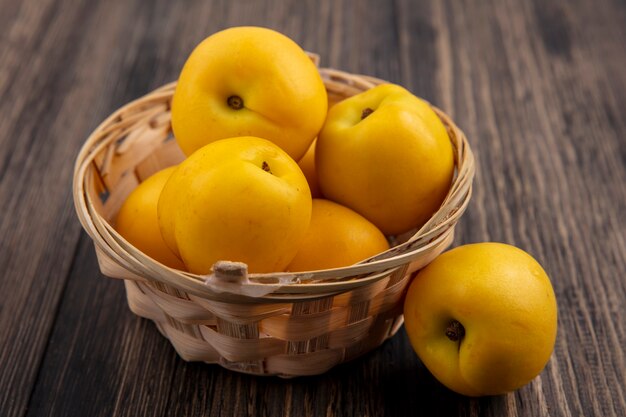 Side view of nectacots in basket on wooden background