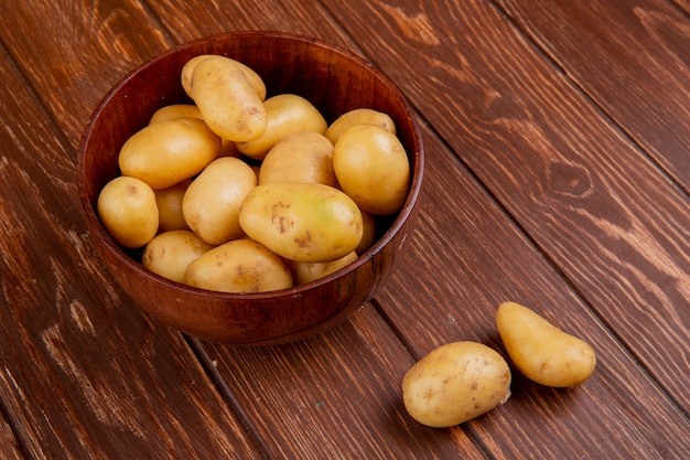 Side view of new potatoes in bowl on wooden table