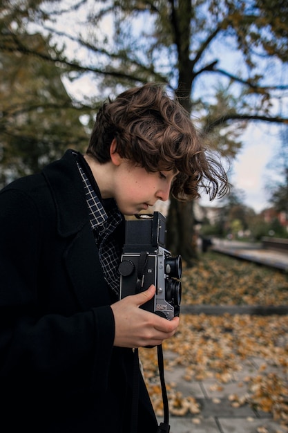 Persona non binaria vista laterale che regola una retro macchina fotografica