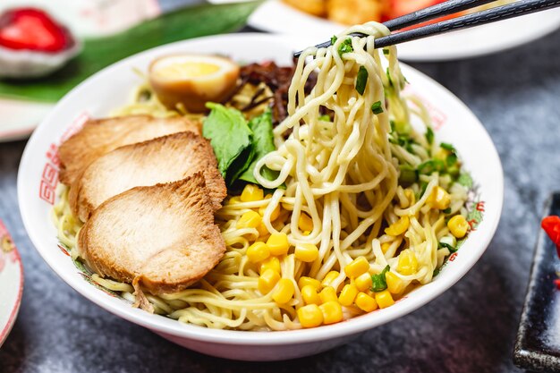 Side view noodles with spring onion basil egg corn and grilled chicken
