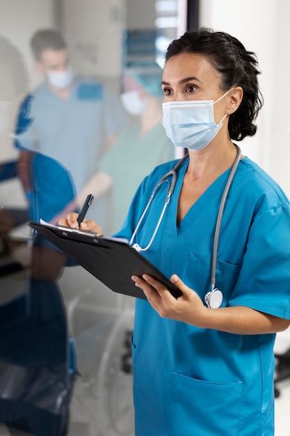 Side view nurse with mask taking notes