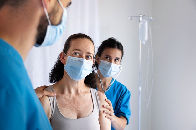 Side view nurses and patient wearing masks