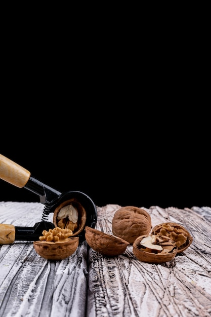 Free photo side view nutcracker and walnuts on wooden table vertical