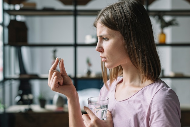 無料写真 病気の若い女性は、錠剤を見ての側面図