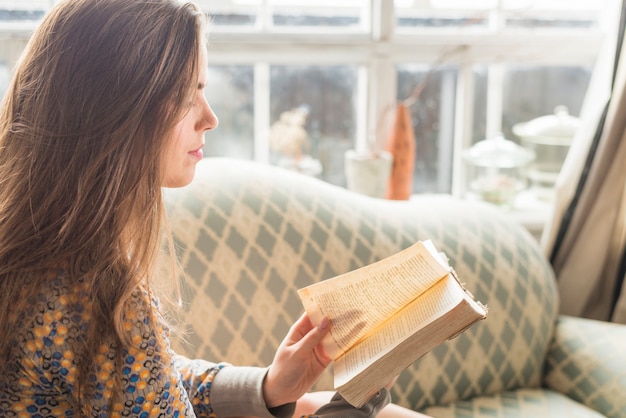 Бесплатное фото Взгляд со стороны молодой женщины поворачивая страницу книги