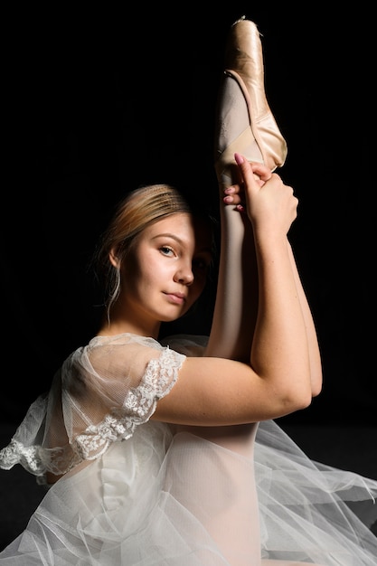 Бесплатное фото Вид сбоку балерины в балетной пачке с растяжкой ноги