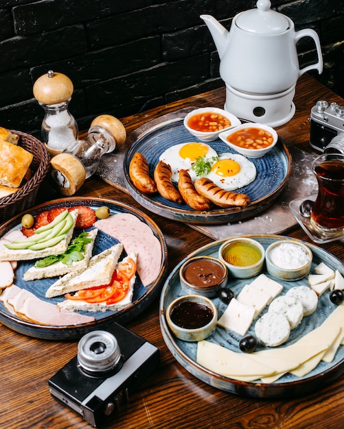 Бесплатное фото Вид сбоку на завтрак стол с жареными яйцами и колбасками свежие овощи сыр и ветчина