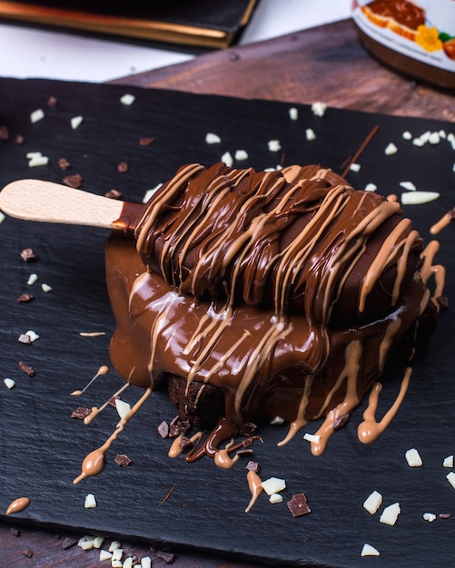 Бесплатное фото Вид сбоку шоколадного мороженого торт на черной деревянной доске