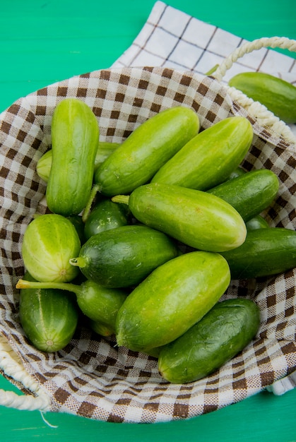 무료 사진 천과 녹색 테이블에 다른 것들과 함께 바구니에 오이의 측면보기