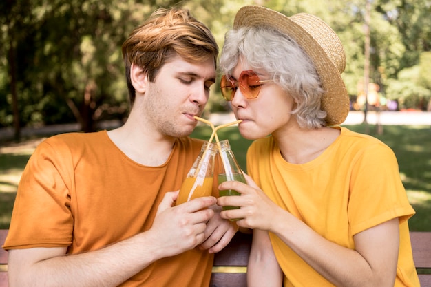 無料写真 ストローで屋外ジュースを飲むかわいいカップルの側面図