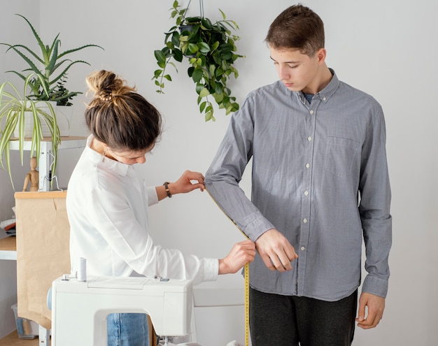 Бесплатное фото Женский портной, измеряющий рубашку клиентов-мужчин, вид сбоку