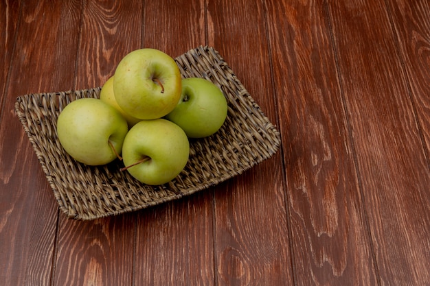 Вид сбоку зеленых яблок в корзине на деревянной поверхности с копией пространства