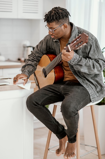 自宅でギターを弾く男性ミュージシャンの側面図