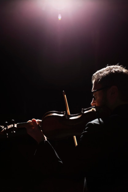Бесплатное фото Вид сбоку на музыканта, играющего на скрипке с копией пространства