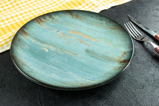 無料写真 暗い表面に青いプレートと黄色のストリップタオルをクロスした食事カトラリーの側面図