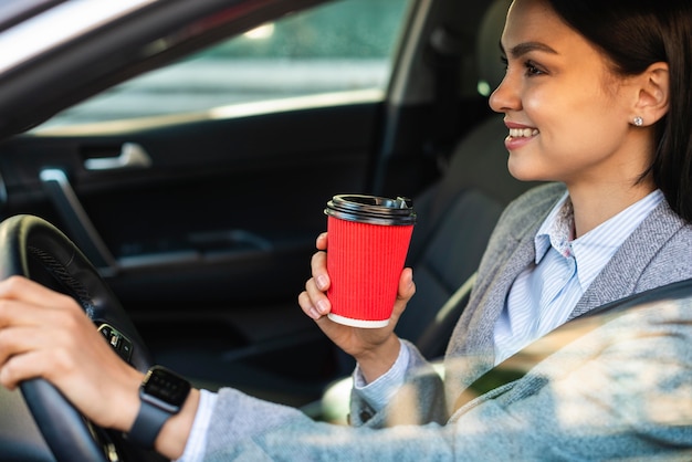 無料写真 運転中にコーヒーを飲んでいる笑顔の実業家の側面図