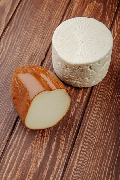Бесплатное фото Вид сбоку копченого сыра с козьим сыром на деревянном деревенском столе