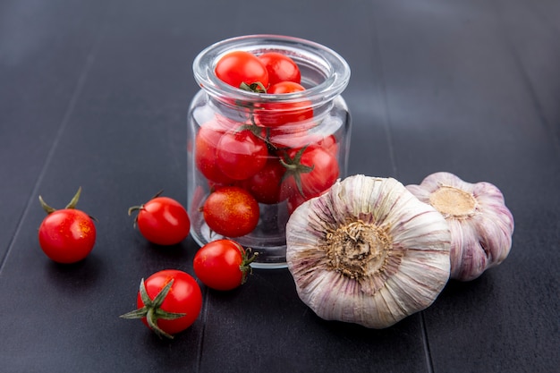無料写真 黒のガラスの瓶とニンニクの球根でトマトとして野菜の側面図