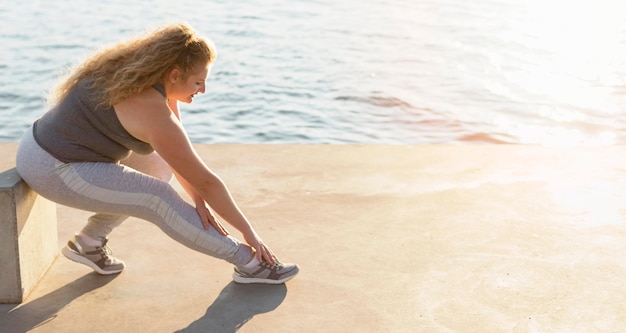Бесплатное фото Вид сбоку женщины, тренирующейся на берегу озера с копией пространства