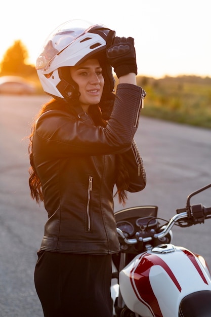 무료 사진 오토바이를 타고 그녀의 헬멧을 씌우고 여자의 측면보기