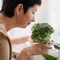 無料写真 屋内植物の匂いを嗅ぐ女性の側面図