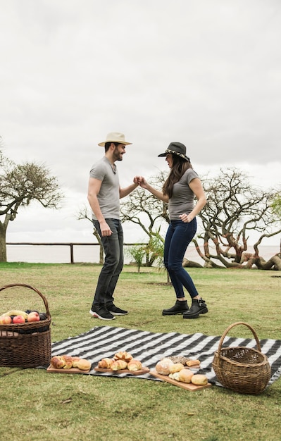 無料写真 公園でピクニックで一緒に踊っている若いカップルの側面図