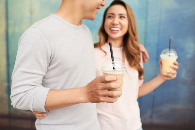 Молодая пара, принимая романтическую прогулку на свидание с молочными коктейлями, вид сбоку