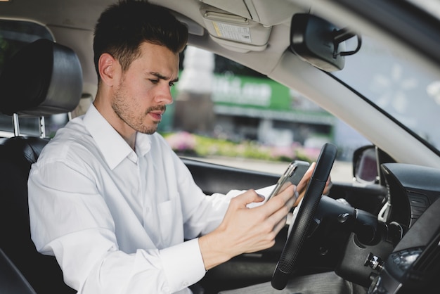 無料写真 車で携帯電話を使用して若いハンサムな男の側面図