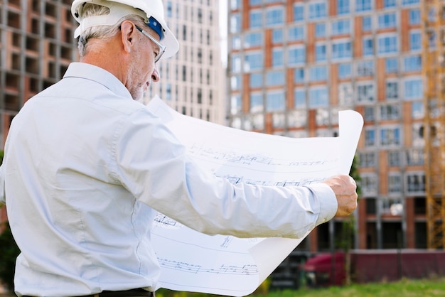 Free photo side view old architect with building plans