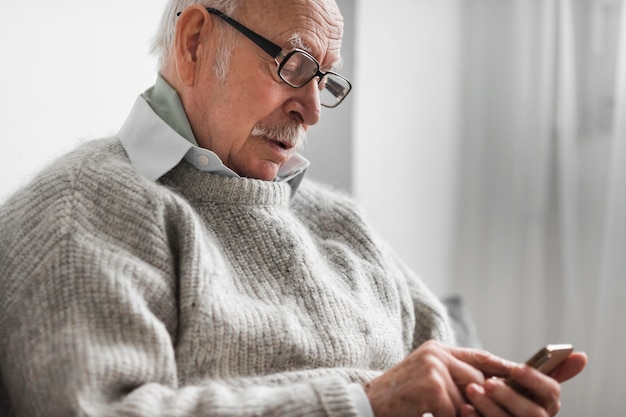 Side view of old man in a nursing home using smartphone