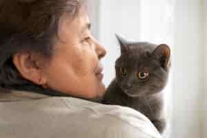 Foto gratuita gatto della holding della donna anziana di vista laterale