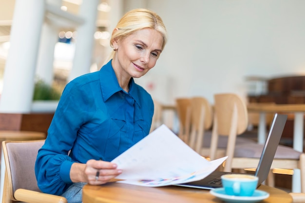 Free photo side view of older business woman dealing with papers