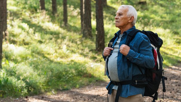 Side view of older man backpacking and exploring nature