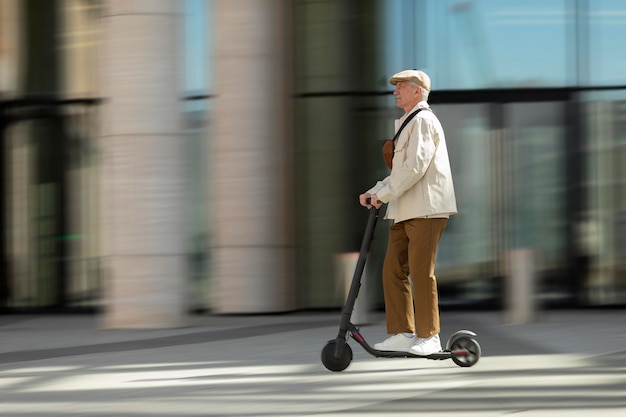 Side view of older man in the city riding an electric scooter