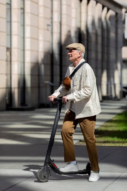 Side view of older man in the city riding an electric scooter