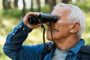 Foto gratuita vista laterale dell'uomo più anziano all'aperto con il binocolo