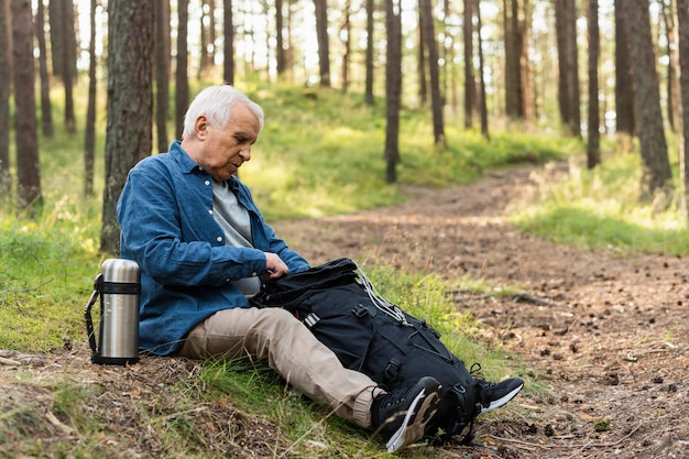 Side view of older man resting while backpacking