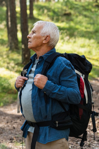 屋外を探索するバックパックで年上の男の側面図