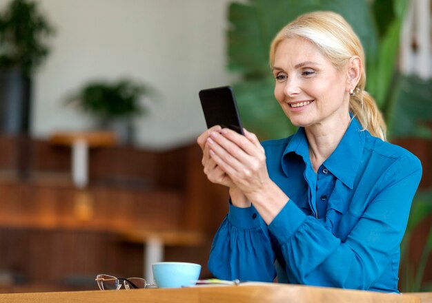 Side view of older woman holding smartphone and smiling