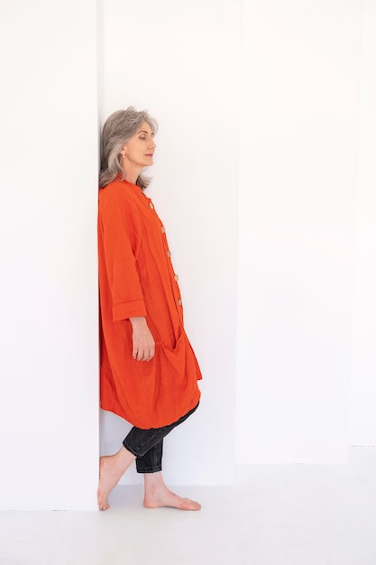 Free photo side view of older woman posing while leaning against the wall