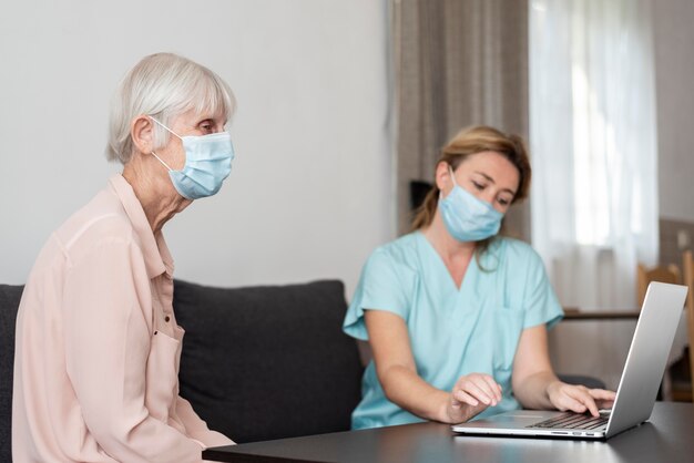 Side view of older woman with female nurse and laptop