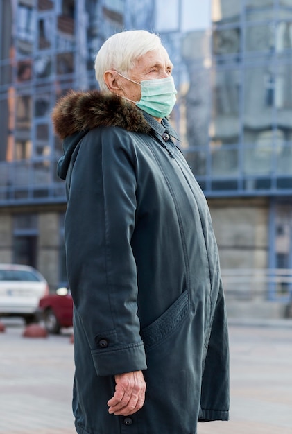 Foto gratuita vista laterale della donna più anziana con maschera medica in città