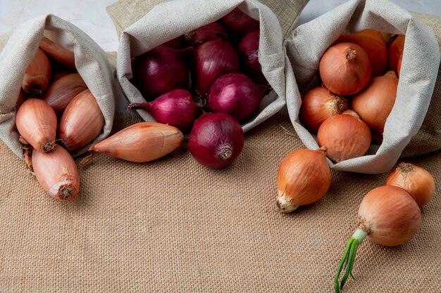 Side view of onions spilling out of sacks on sackloth surface with copy space