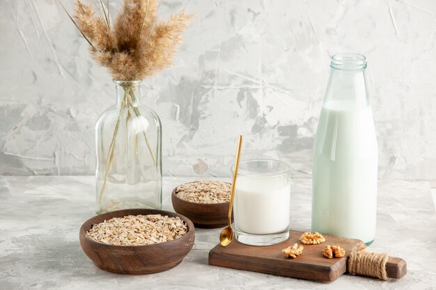 Side view of open glass bottle cup filled with milk spoon and walnut oats in brown pot on ice wall