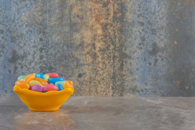 Side view of orange bowl full with jellybean candies. 